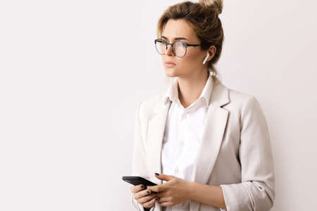 Young businesswoman talking by phone using wireless earbudsの写真素材