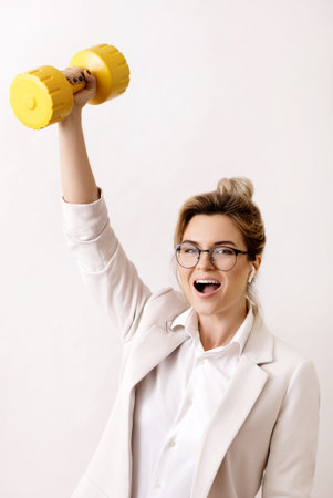Happy successful business woman is lifting heavy dumbbell
