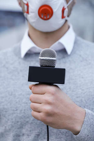 News reporter wearing a prevention mask and speaking into a microphoneの写真素材