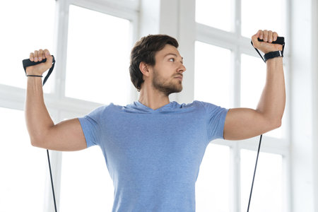 Young man during workout with a resistance bands in the gym