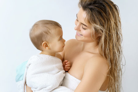 Young and happy mother and her cute little baby after bathing
