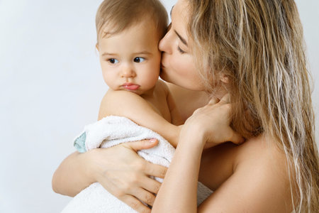 Young and happy mother and her cute little baby after bathing