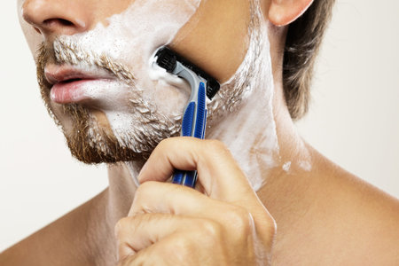 Man with a safety razor and shaving cream on his face