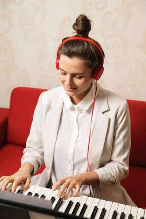 Young woman musician playing synthesizer at homeの写真素材