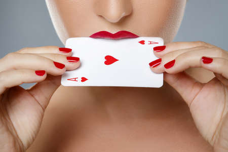 Woman with red lips is holding ace card in her handsの写真素材