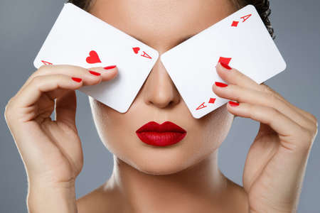 Woman with red lips is holding two aces in her handsの写真素材
