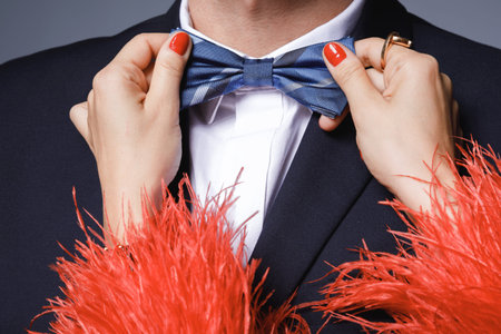 Woman is helping to fit up a bow tie to her man