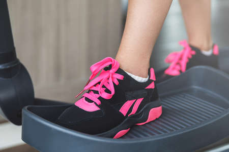 Female legs on a elliptical trainer in the gymの写真素材