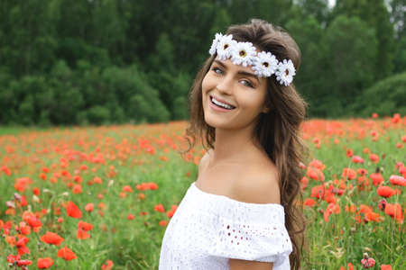 Beautiful woman in field with a lot of poppy flowersの写真素材