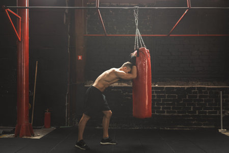 Fighter is very tired during his workout with a punching bag