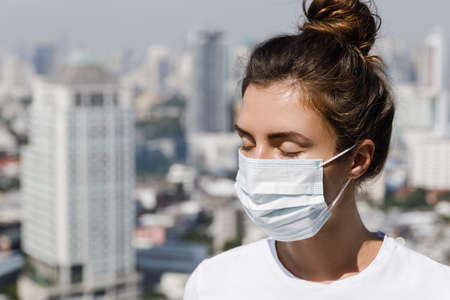 Woman wearing face mask because of air pollution or virus pandemic in the cityの写真素材