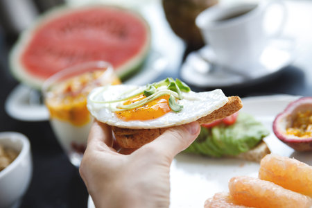 Woman is eating toast with a fried egg.