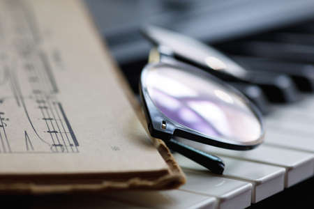 Sheet music and eyeglasses on the piano keysの写真素材