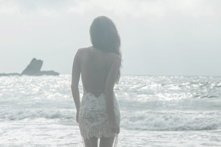 Woman wearing beautiful white dress is posing on the beach