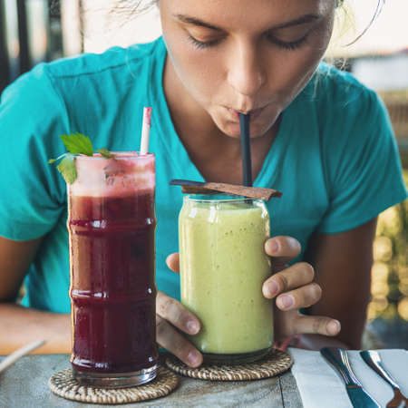 Woman is tasting different healthy drinks in vegan cafeの写真素材