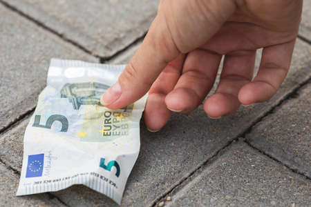 Woman is picking five euro banknote from the groundの写真素材