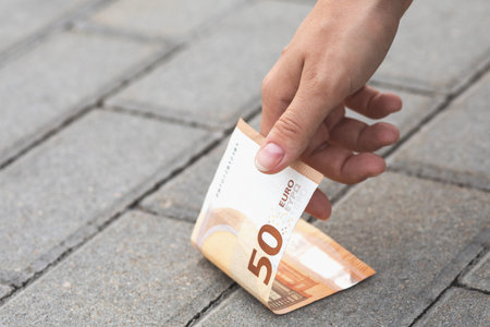 Woman is picking fifty euro banknote from the ground.