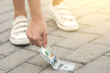 Lucky woman is picking one hundred dollars bill from the ground.の写真素材