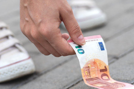 Woman is picking ten euro banknote from the groundの写真素材