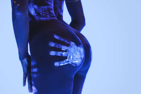 Female body with fluorescent bodyart paint in ultraviolet light.の写真素材