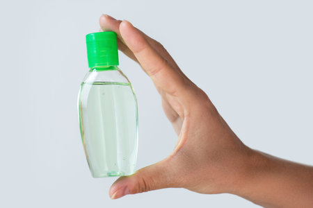 Hand with a small bottle of hand sanitizer