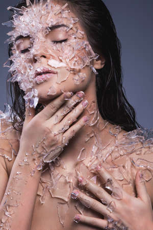 Female face covered with a lot small pieces of glass or iceの写真素材