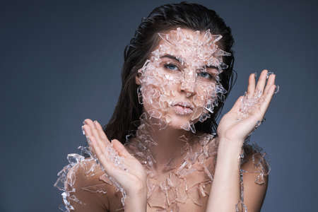 Female face covered with a lot small pieces of glass or iceの写真素材