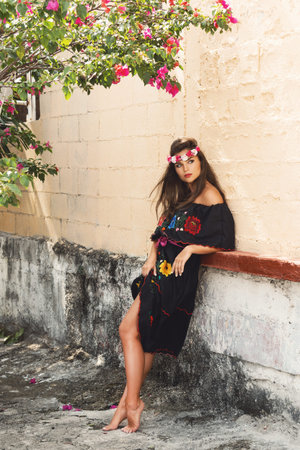 Young beautiful woman wearing traditional mexican dress on the city street