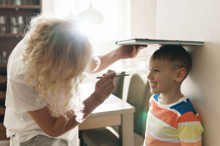 Mother playfully measuring the height of her sonの写真素材