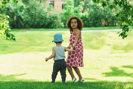 Cute African girl and little caucasian boy in a city park