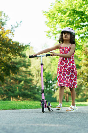 Little black girl with a kick scooter in a city parkの写真素材