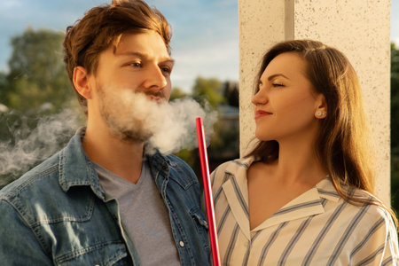 Young happy couple smoking hookah on a balcony