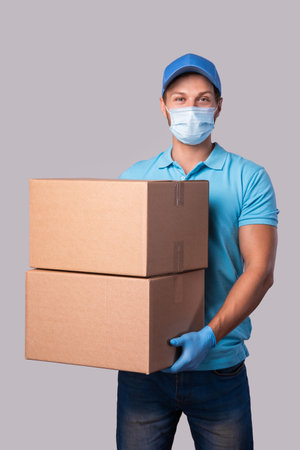 Young delivery man is wearing prevention mask and gloves with a cardboard boxesの写真素材