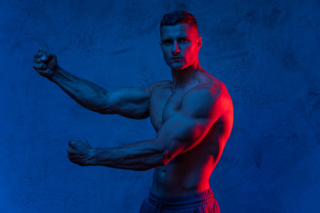 Muscular man posing in the colorful lightの写真素材