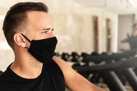 Young athletic man wearing a prevention face mask during his workout in the gymの写真素材