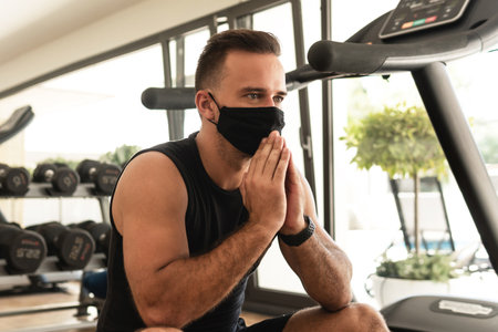 Young athletic man wearing a prevention face mask during his workout in the gymの写真素材