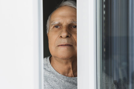 Lonely elderly man looking into the window