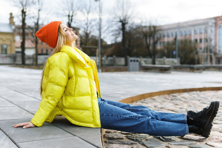Stylish girl wearing yellow puffer and orange knitted hatの写真素材