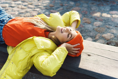 Stylish girl wearing yellow puffer and orange knitted hatの写真素材