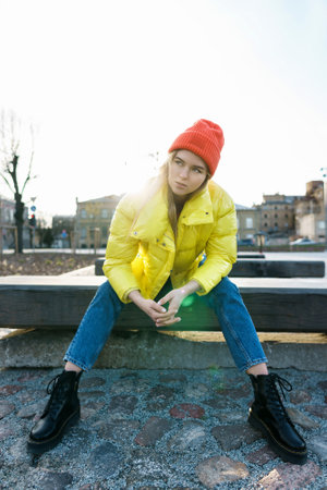 Stylish girl wearing yellow puffer and orange knitted hatの写真素材