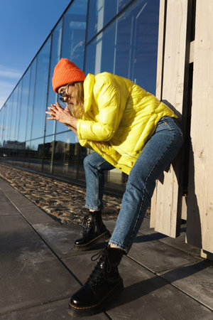 Stylish girl wearing yellow puffer and orange knitted hat