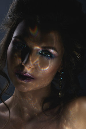 Beautiful woman in darkness with a light reflection on her face
