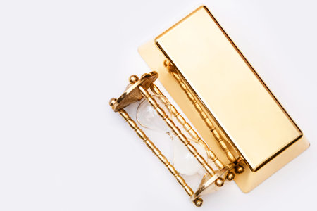 Hourglass and fine gold bullion on white background