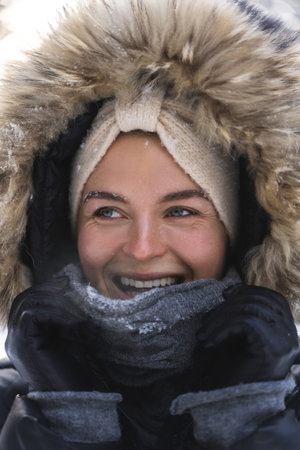 Young and cheerful woman wearing jacket with a hoodie during cold winter day