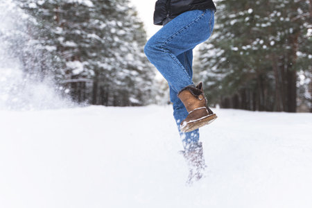 Woman wearing sheepskin boots is kicking snowの写真素材