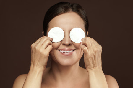 Beautiful middle aged woman with a cotton pads for face cleaning or make-up removal routineの写真素材