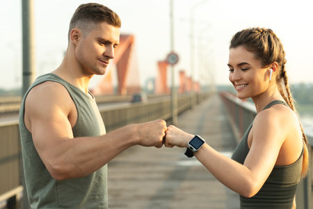 Athletic couple making fist bump gesture during fitness workout on city streetの写真素材
