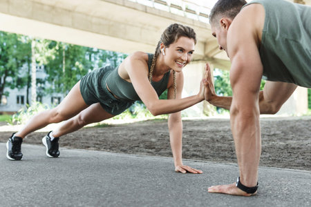 Athletic couple and fitness training outdoors. Man and woman doing push-ups exercise.