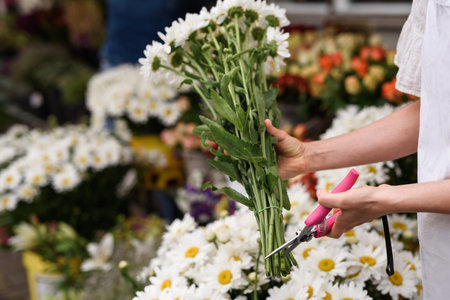 Woman florist cutting lower edge of flowers with sharp secateursの写真素材