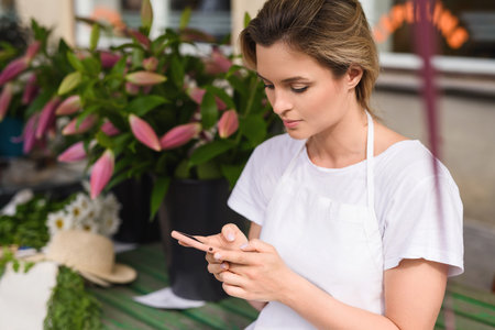 Woman florist using smartphone in her little flower shopの写真素材